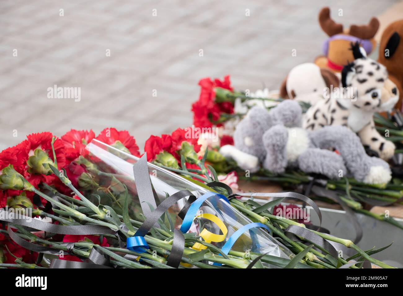 Spielzeug und Blumen liegen an einer Trolleybushaltestelle neben einem Haus, das während des Krieges von einer russischen Rakete auf Pobeda in der Stadt Dnepr in der Ukraine in die Luft gejagt wurde, dem M. Stockfoto