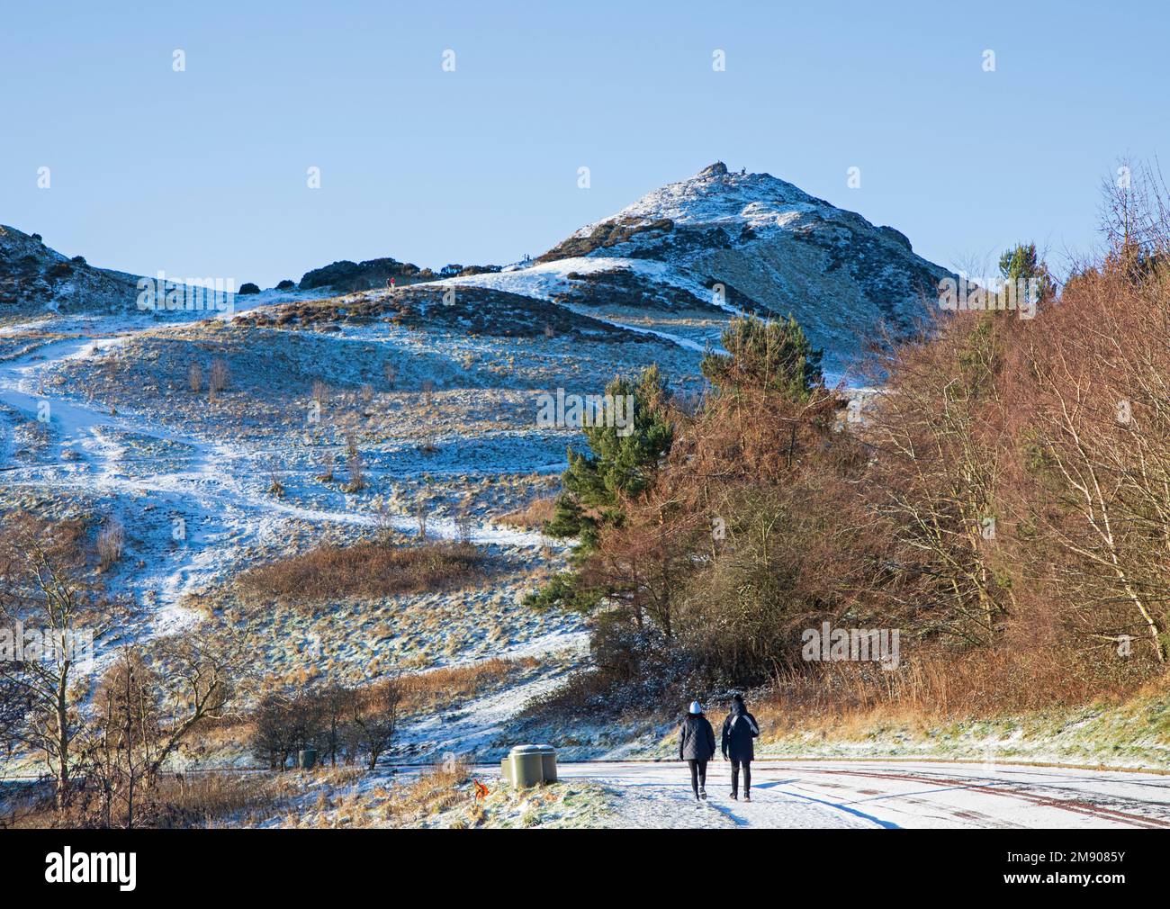 Holyrood Park, Edinburgh, Schottland, Großbritannien. 16. Januar 2023 Schneebedeckung und vereiste Straßen und Gehwege in der schottischen Hauptstadt, Morgentemperatur minus 3 Grad Celsius. Abbildung: Ein Spaziergang auf dem eisigen Bürgersteig mit dem Gipfel von Arthur's Seat im Hintergrund. Kredit: ArchWhite/alamy Live News. Stockfoto