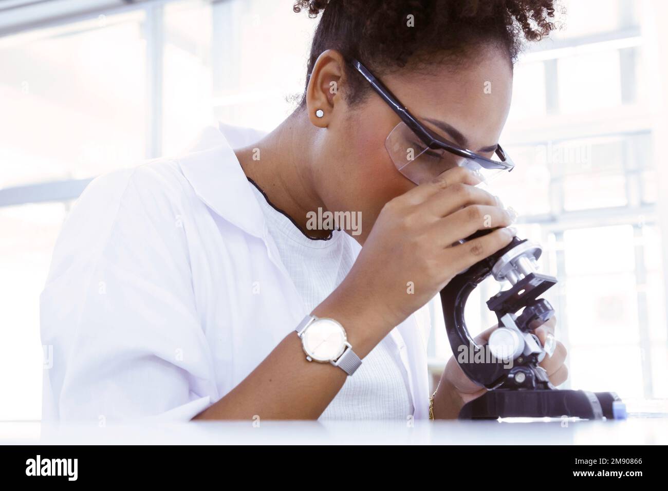 Schwarze weibliche Ärztin Studentin Wissenschaftlerin schaut Mikroskop tut Analyse Virus-Test Probe. Junger Biotechnologie-Spezialist im Labor. Medizinische Wissenschaft Stockfoto