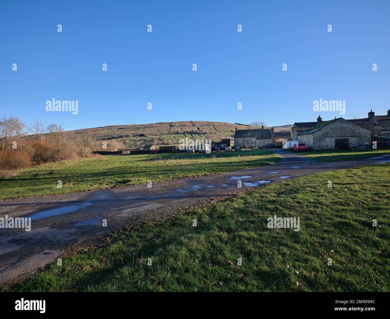 Eine Gruppe von Bauernhöfen mit hellblauem Himmel, fernen Hügeln und rauen Bauernhöfen im Vordergrund Stockfoto