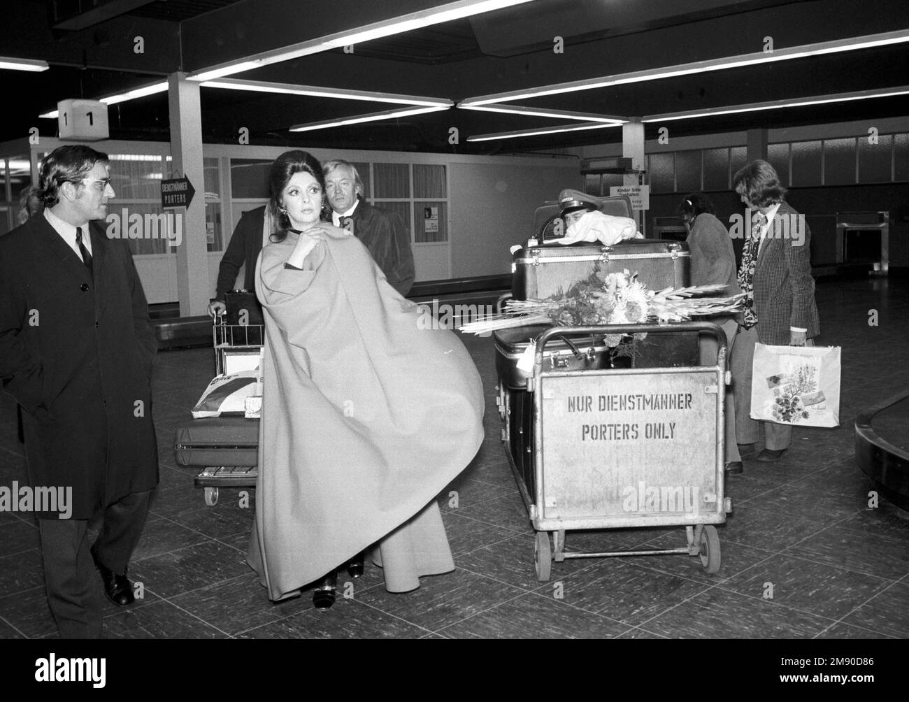 ARCHIVFOTO: Gina LOLLOBRIGIDA starb im Alter von 95 Jahren, Schauspielerin Gina LOLLOBRIGIDA, Italien, bei ihrer Ankunft am Flughafen München-Riem am 10. Oktober 1971., in einem Umhang verpackt, transportierte ein Gepäckträger ihre Koffer auf einem Trolley, Gepäckwagen, S/W-Aufzeichnung, 10/10/1971. ? Stockfoto