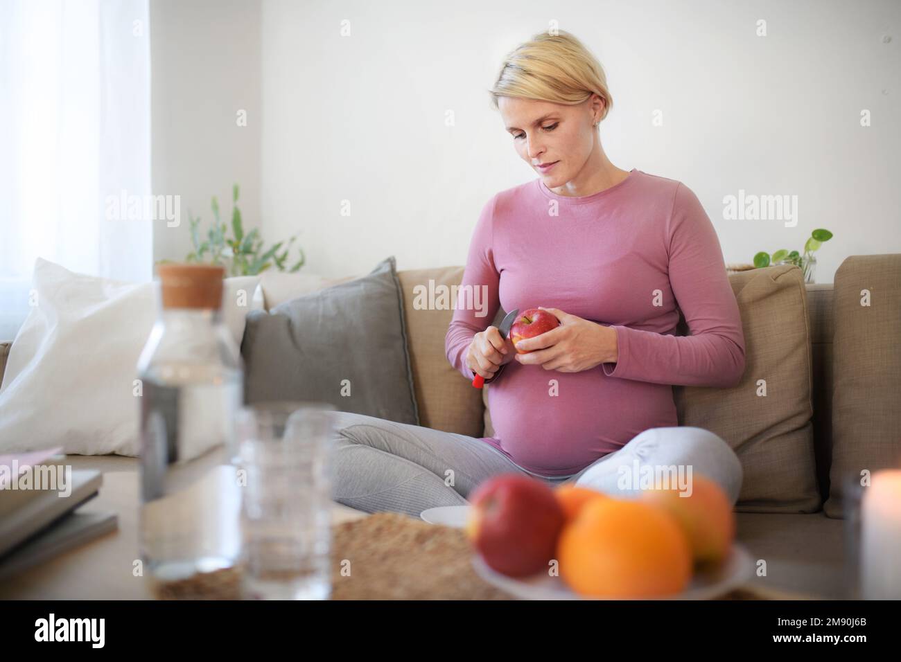 Aus dem Blickwinkel einer schwangeren Frau, die Apfel schneidet. Stockfoto