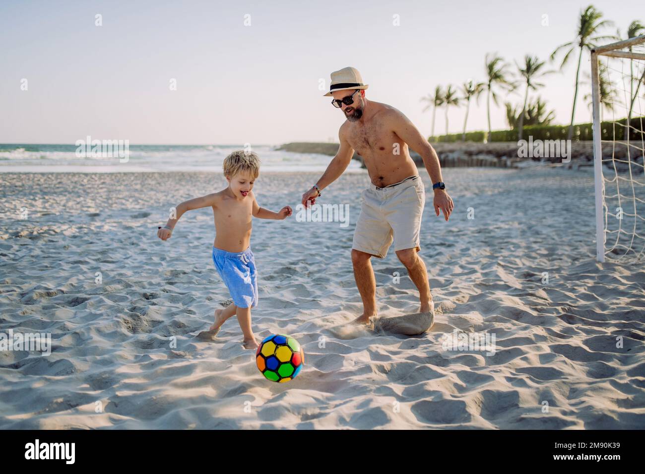 Vater und sein Sohn spielen Fußball am Strand. Stockfoto