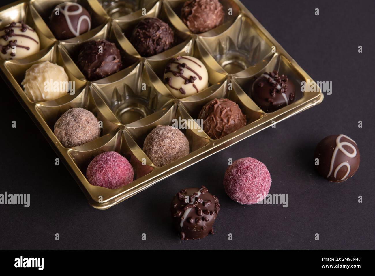 Fotobonbons, die in einem Paket neben dem Paket liegen, sind ein paar Süßigkeiten auf schwarzem Hintergrund Stockfoto