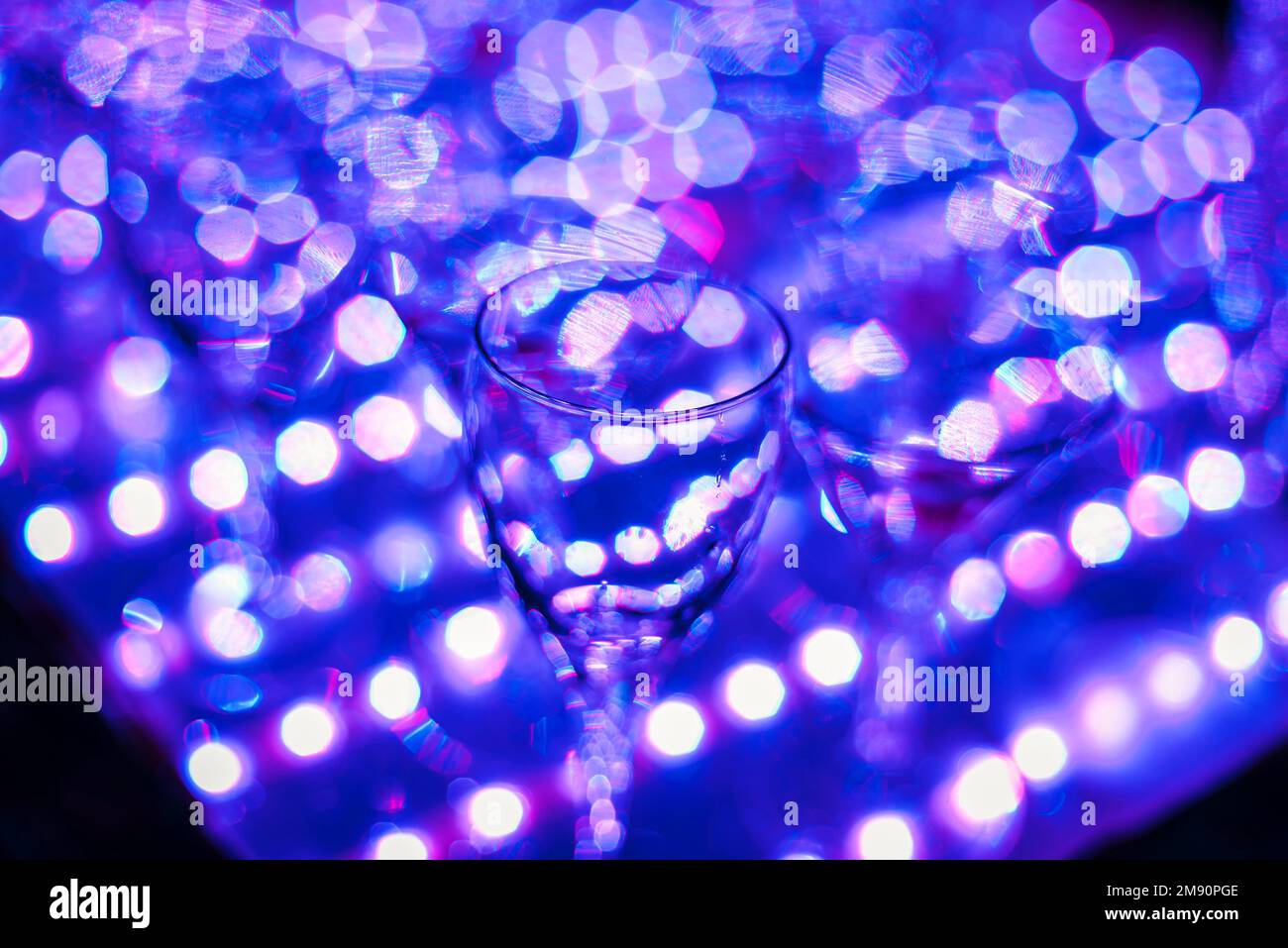 Leere Cocktailgläser mit heller Hintergrundbeleuchtung, ultraviolette Farbe mit Fokus im Vordergrund und verschwommenem Hintergrund Stockfoto