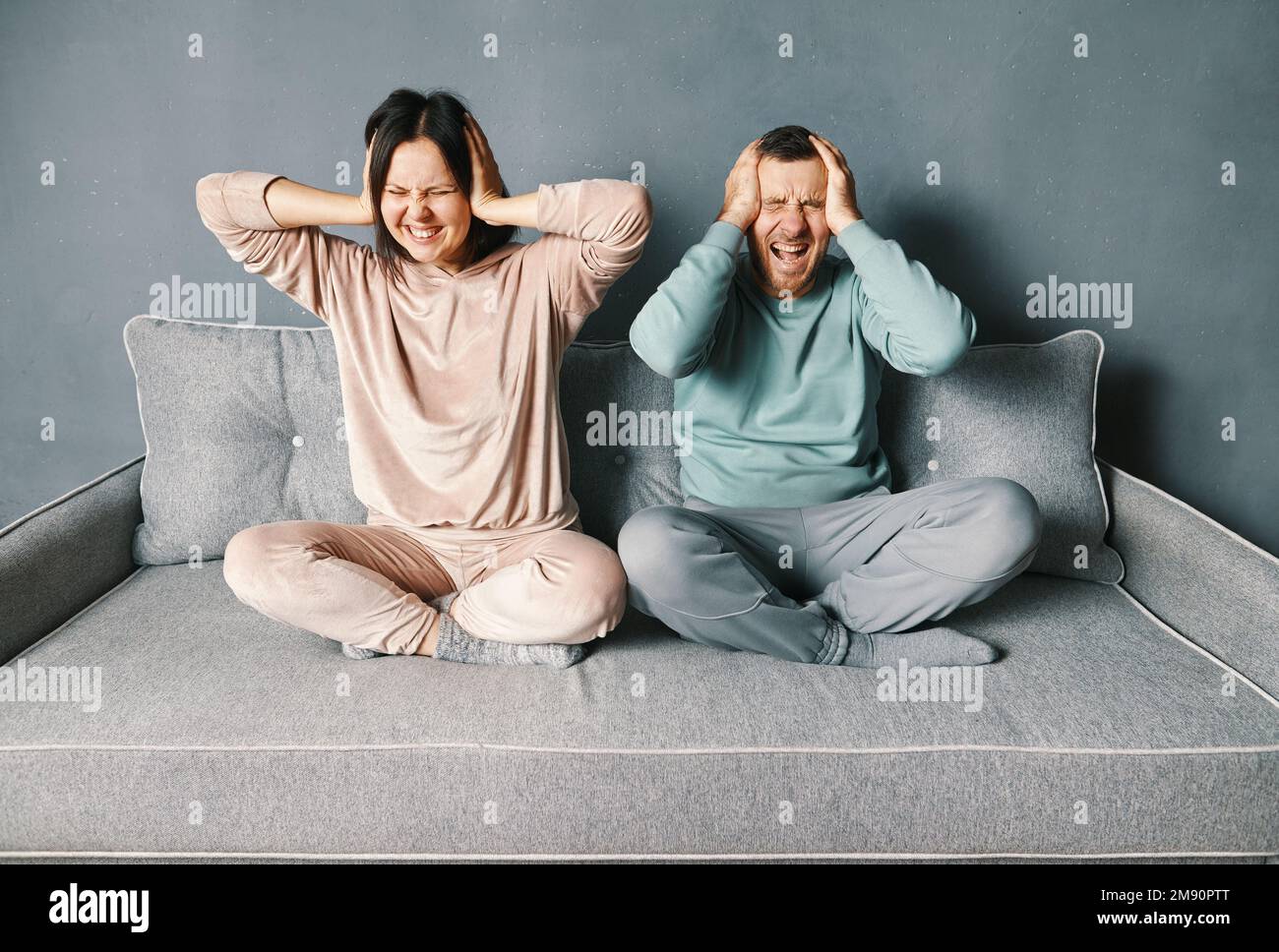 Gestresstes verzweifeltes Paar, das sich die Ohren schließt, mit beiden Händen gereizt, mit lautem, nervigem Lärm, Kopfschmerzen oder Migräne. Negative menschliche Emotionen. Psychiater Stockfoto