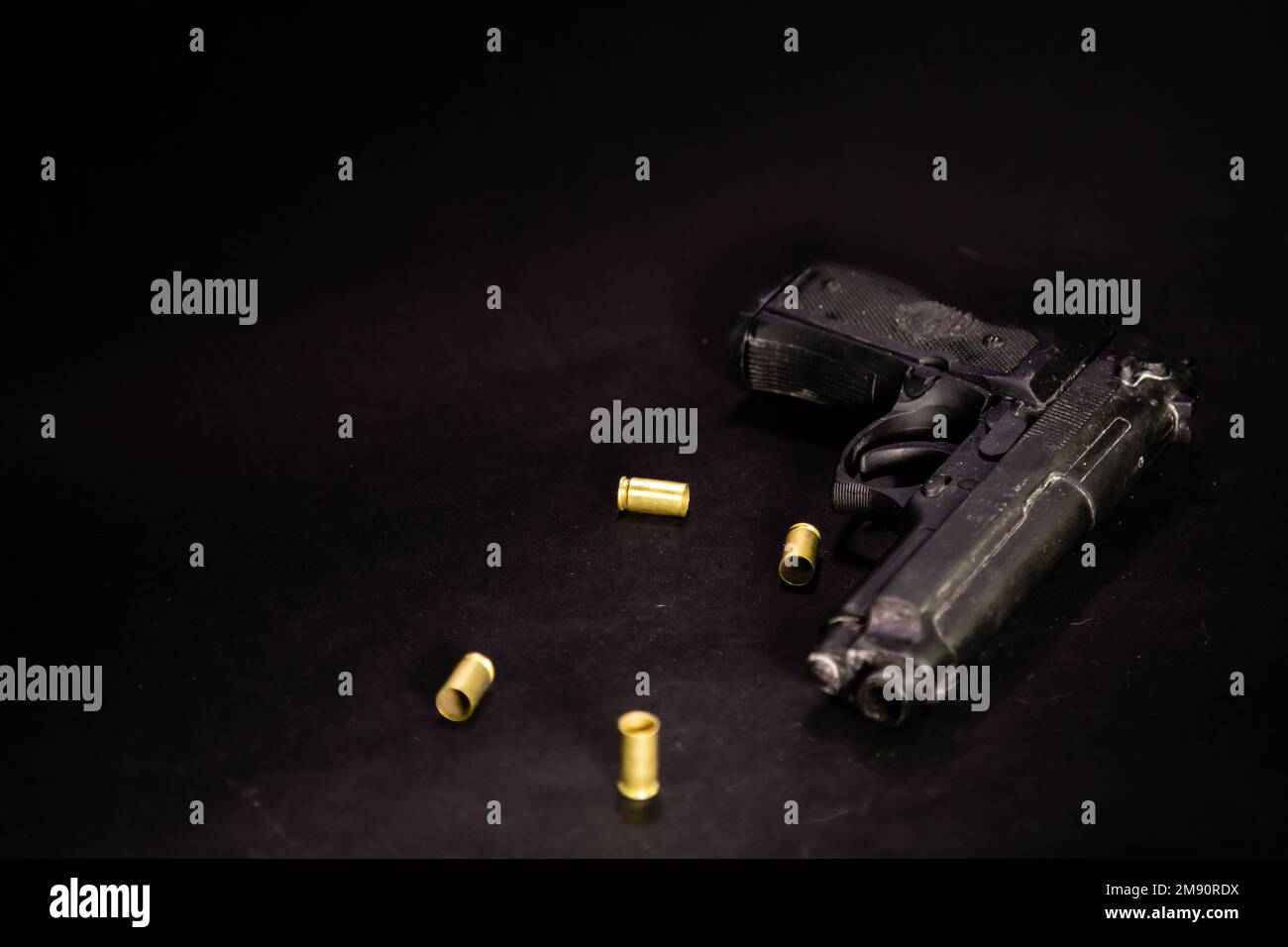 Pistole mit 9mm Patronenhülsen auf schwarzem Hintergrund, Makroaufnahme Stockfoto