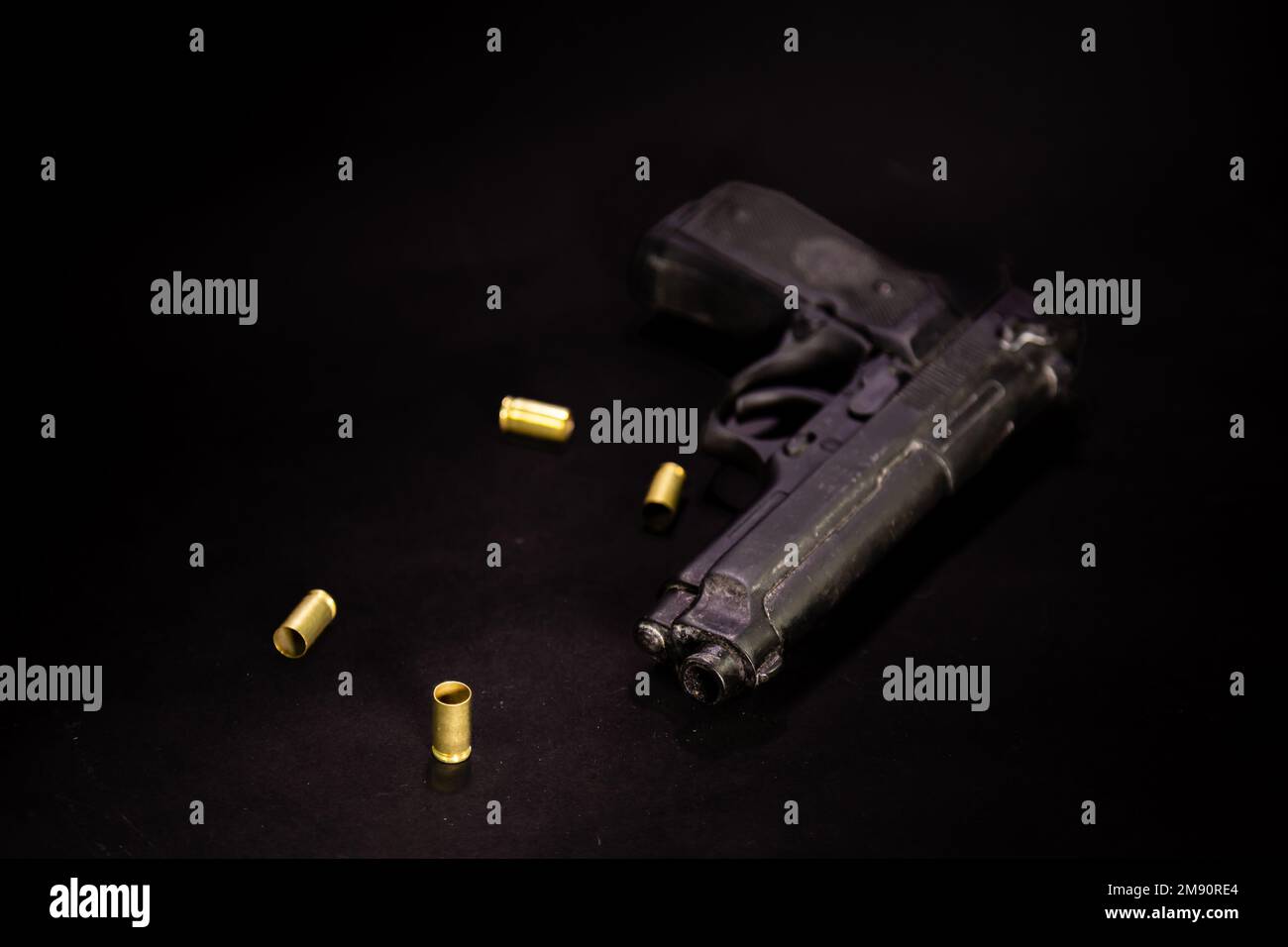 Pistole mit 9mm Patronenhülsen auf schwarzem Hintergrund, Makroaufnahme Stockfoto