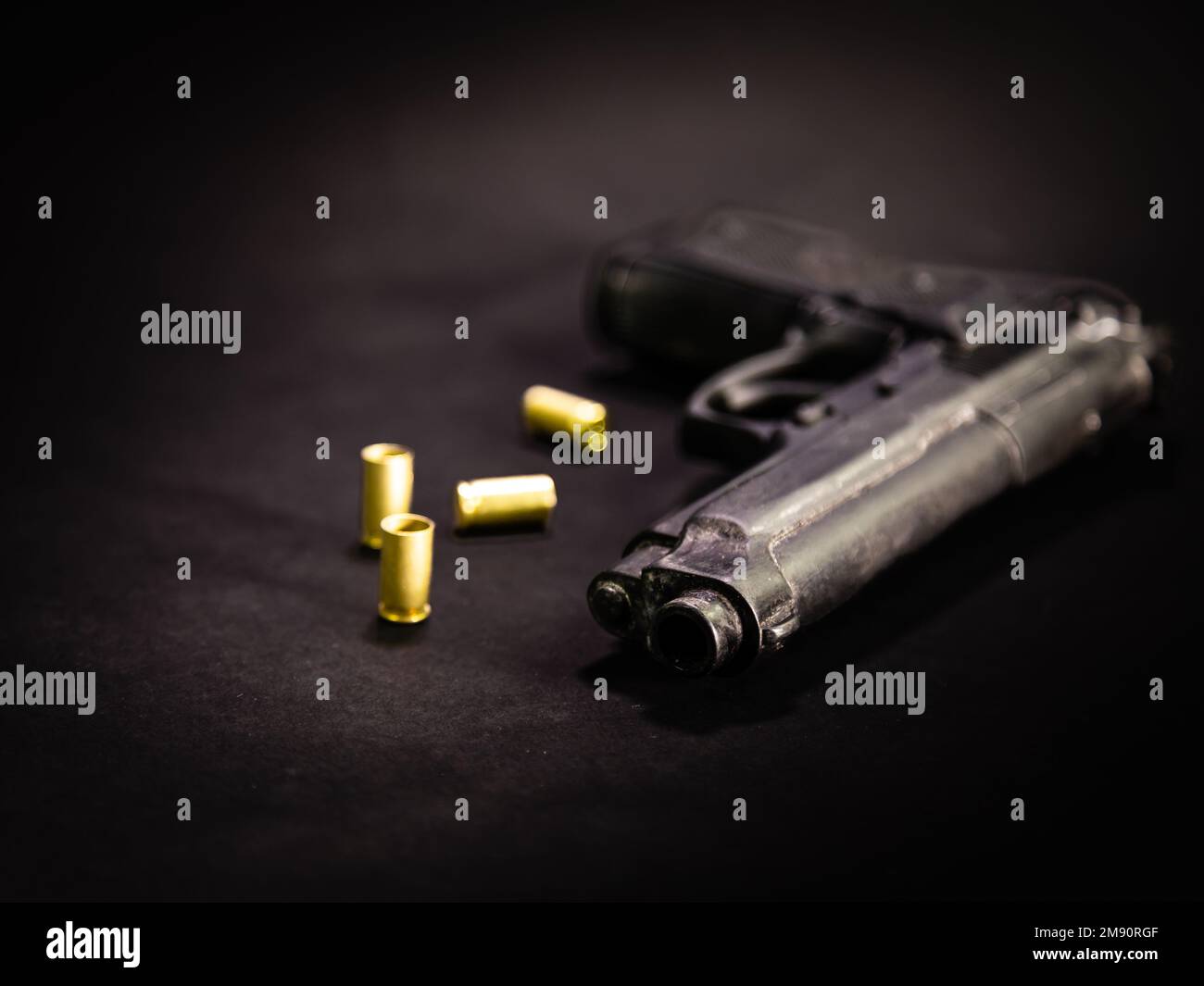 Pistole mit 9mm Patronenhülsen auf schwarzem Hintergrund, Makroaufnahme Stockfoto