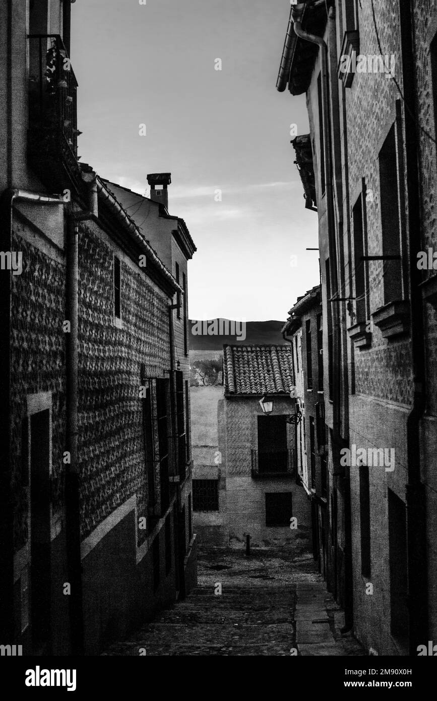 Von einer schmalen Straße mit einem kleinen Kamin aus in Segovia, Spanien, können Sie die Silhouettendächer historischer Gebäude in vertikaler Richtung betrachten Stockfoto