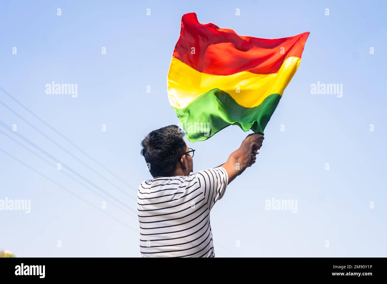 Rückansicht eines Mannes, der die schwarze Flagge des historischen Monats gegen den Himmel schwenkt - Konzept von Freiheit, Unabhängigkeit und Feier Stockfoto