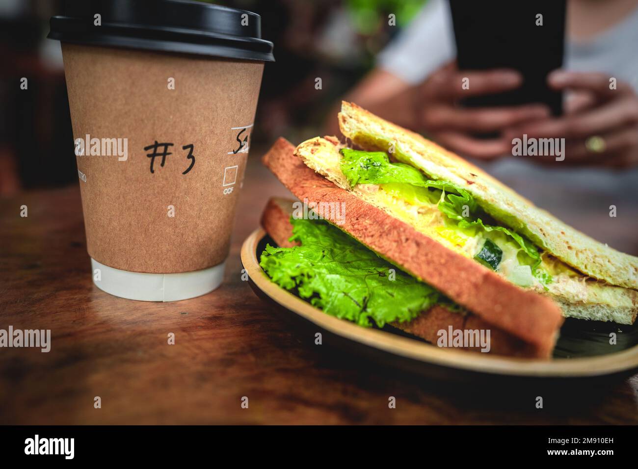 Ein kurzer Happen Sandwich mit Kaffee für den Start in den Tag. Stockfoto