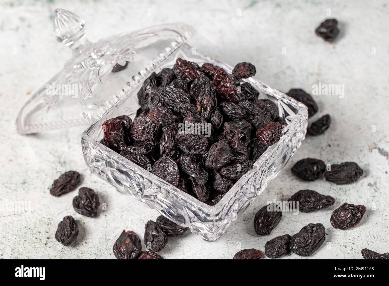Getrocknete schwarze Trauben auf Steinhintergrund. Getrocknete Trauben in Glasschale. Nusssorten. Gesunde Ernährung. Schließen Stockfoto