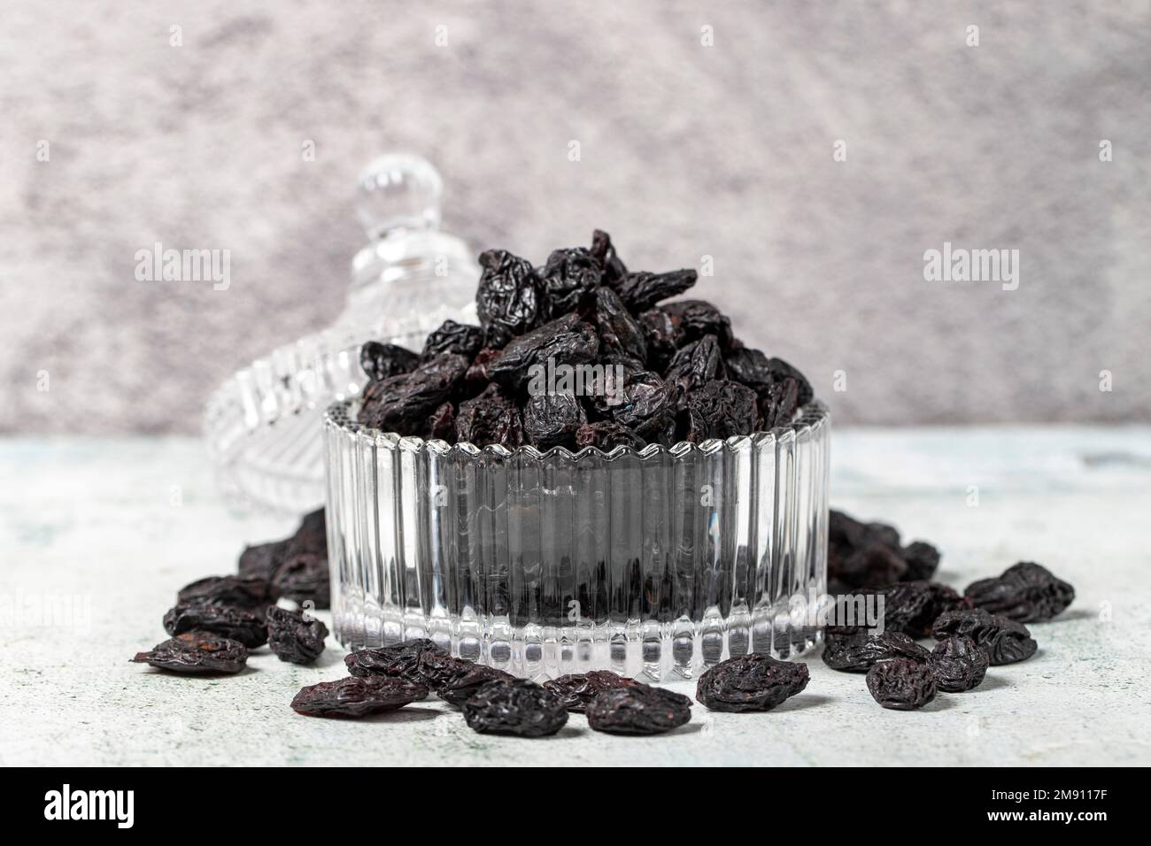 Getrocknete schwarze Trauben auf Steinhintergrund. Getrocknete Trauben in Glasschale. Nusssorten. Gesunde Ernährung. Schließen Stockfoto