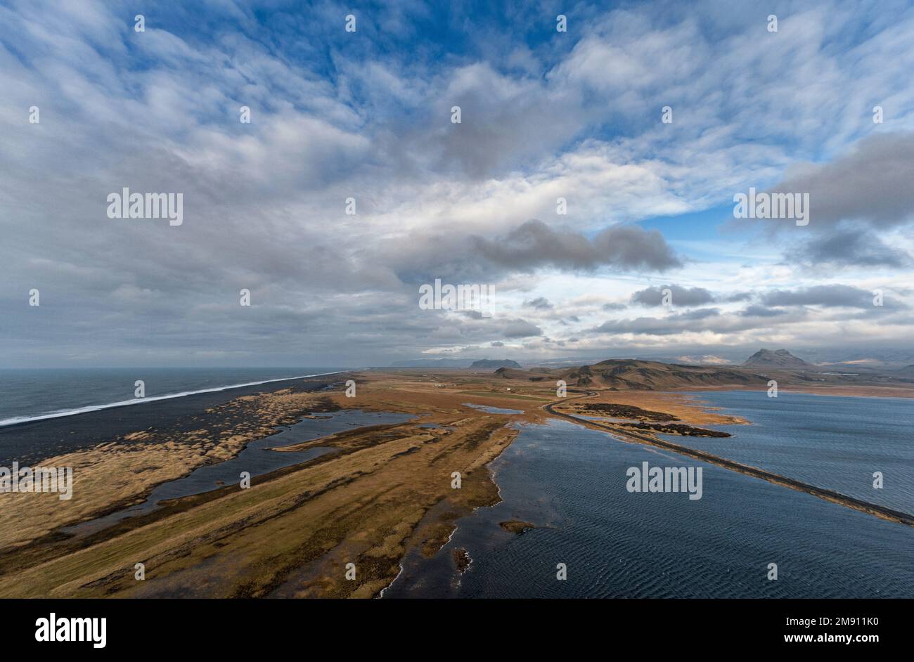 Landschaft Islands mit Bergen, wolkigem Himmel und leerer Straße. Stockfoto