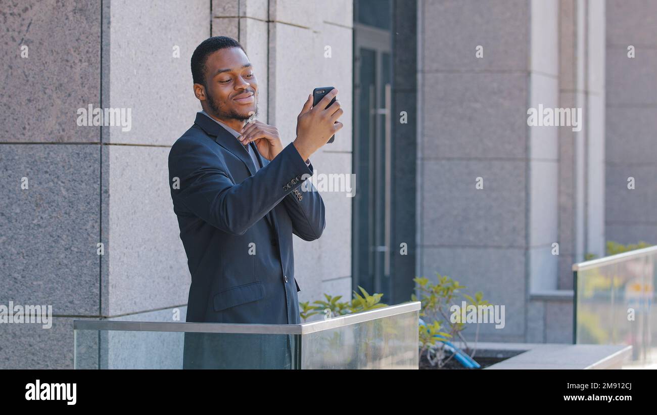 Afroamerikanischer Büroangestellter steht auf dem Balkon und spricht mit Kollegen über eine Smartphone-Video-Chat-App. Ethnischer Geschäftsmann, Unternehmer-Manager Stockfoto