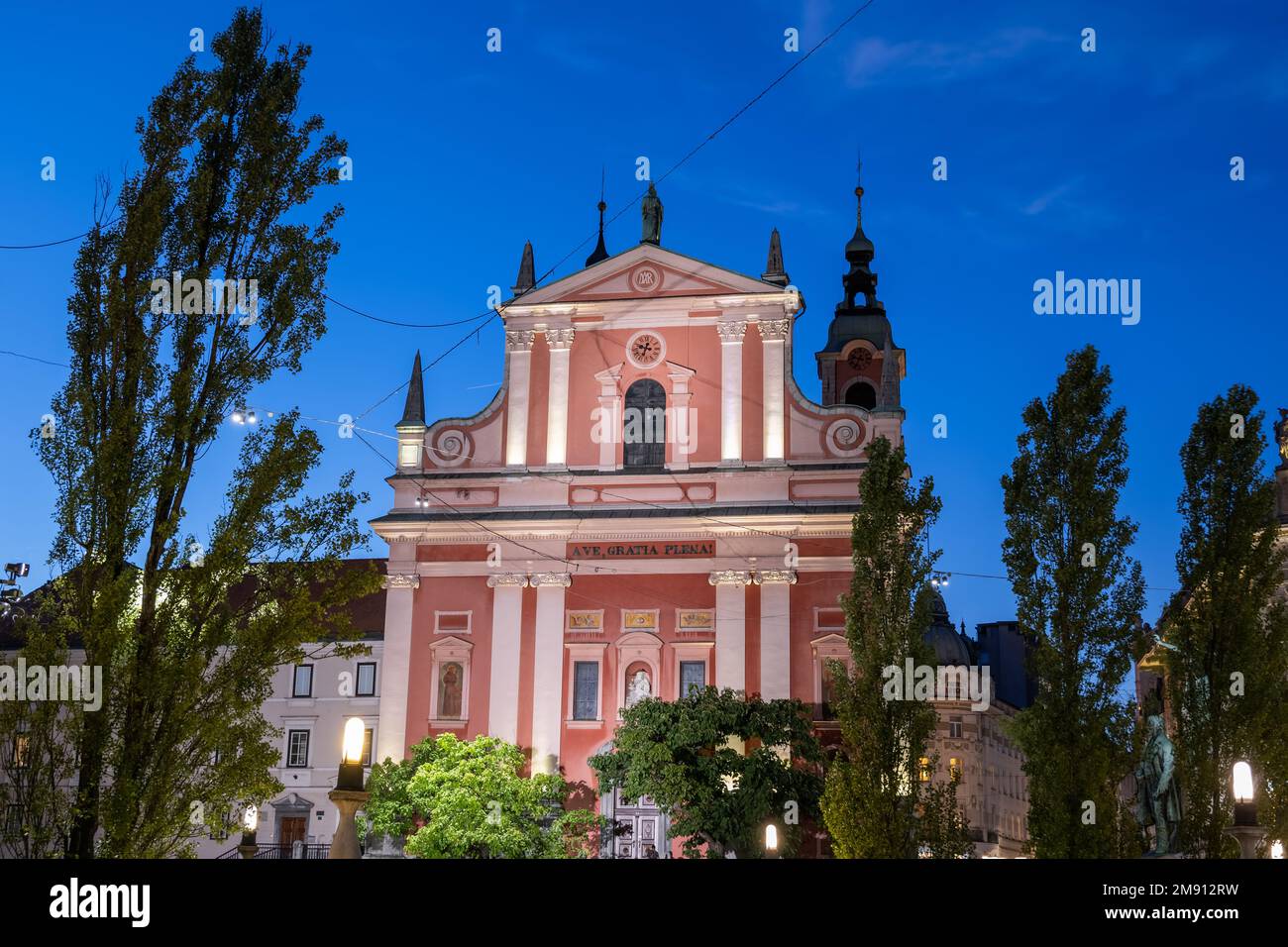 Die Franziskanerkirche der Verkündigung bei Nacht in Ljubljana, Slowenien. Beleuchtete barocke Fassade aus dem Jahr 1703, Wahrzeichen der Stadt. Stockfoto