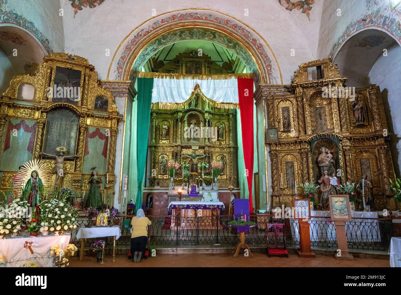 Eine kniende Frau betet im Schiff der katholischen Pfarrkirche Santa Ana Zegache in Oaxaca, Mexiko. Stockfoto