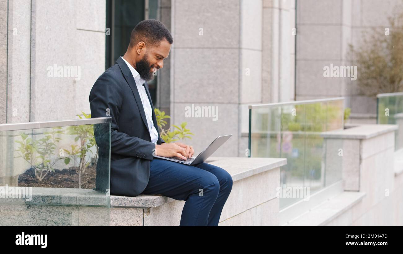 Afroamerikanischer ethnischer Geschäftsmann Freiberufler Unternehmer Executive Arbeitgeber Ethnischer Geschäftsmann, der mit einem Laptop im Freien in der Nähe arbeitet Stockfoto