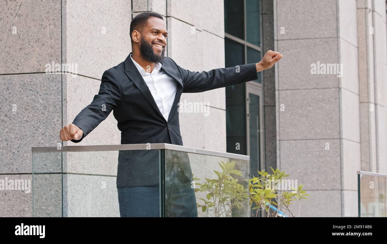 Fröhliche, lustige, fröhliche, afrikanische, ethnische Unternehmer-Führungskraft feiert gute Nachrichten, den Sieg mit lustigem Tanz. Amerikanischer Angestellter Unternehmer Stockfoto