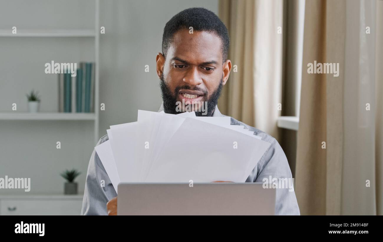 Wütender, frustrierter afroamerikanischer Mann, ethnisch bärtiger Geschäftsmann, Chef, der Papiere verwaltet, die sich Dokumente ansehen, Fehler, enttäuscht von Papierkram Stockfoto