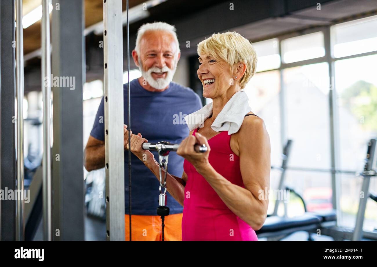 Glückliche Senioren, die im Fitnessstudio Übungen machen, um fit zu bleiben. People Sport Konzept. Stockfoto