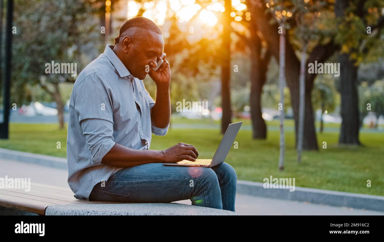 Afroamerikanischer ethnischer Mann mittleren Alters professioneller Geschäftsmann Freiberufler Unternehmer Arbeitgeber, der mit dem Smartphone spricht, telefonisch mit Kundenhilfe sprechen Stockfoto