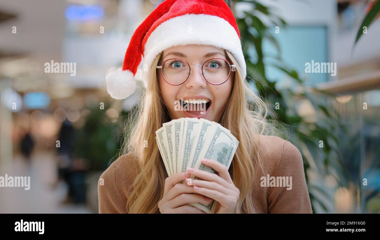 Nahaufnahme reiche, weiße, glückliche Erfolgsfrau Lady in rotem Weihnachtsmann Hut Mütze und Brille mit Geld Dollars Bargeld Kredit finanzieller Preis gewonnen Stockfoto