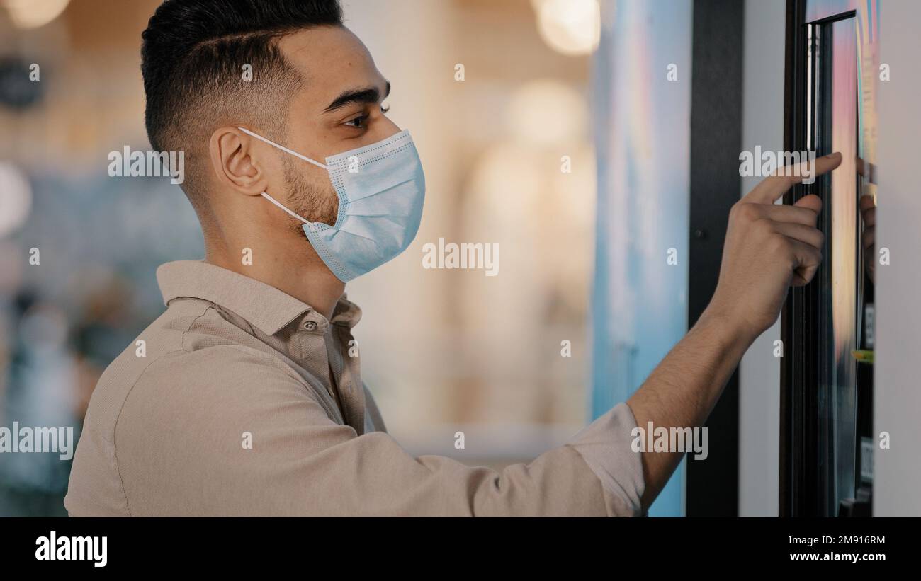 Seitenansicht männlicher Passagier indischer Hispanic Mann in medizinischer Maske im Flughafen Terminal Geschäftsmann im Bankbüro mit Selbstbedienungsautomat Online-Zahlung Stockfoto