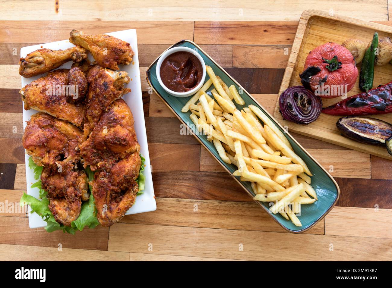 Gebackenes Hähnchen in Adjika-Gewürzen, gebackenes Gemüse und pommes frites, abchasische Küche, auf Holztisch, Tiflis, Georgia Stockfoto