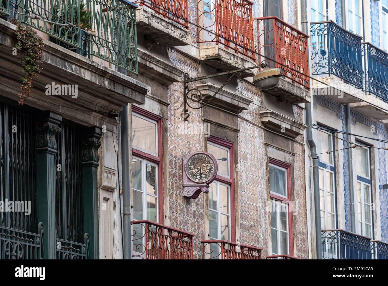 Alte, verfallene Uhr an der Wand auf einem Apartmentgebäude im klassischen portugiesischen Stil mit traditionellen Fliesen in Lissabon, Portugal Stockfoto