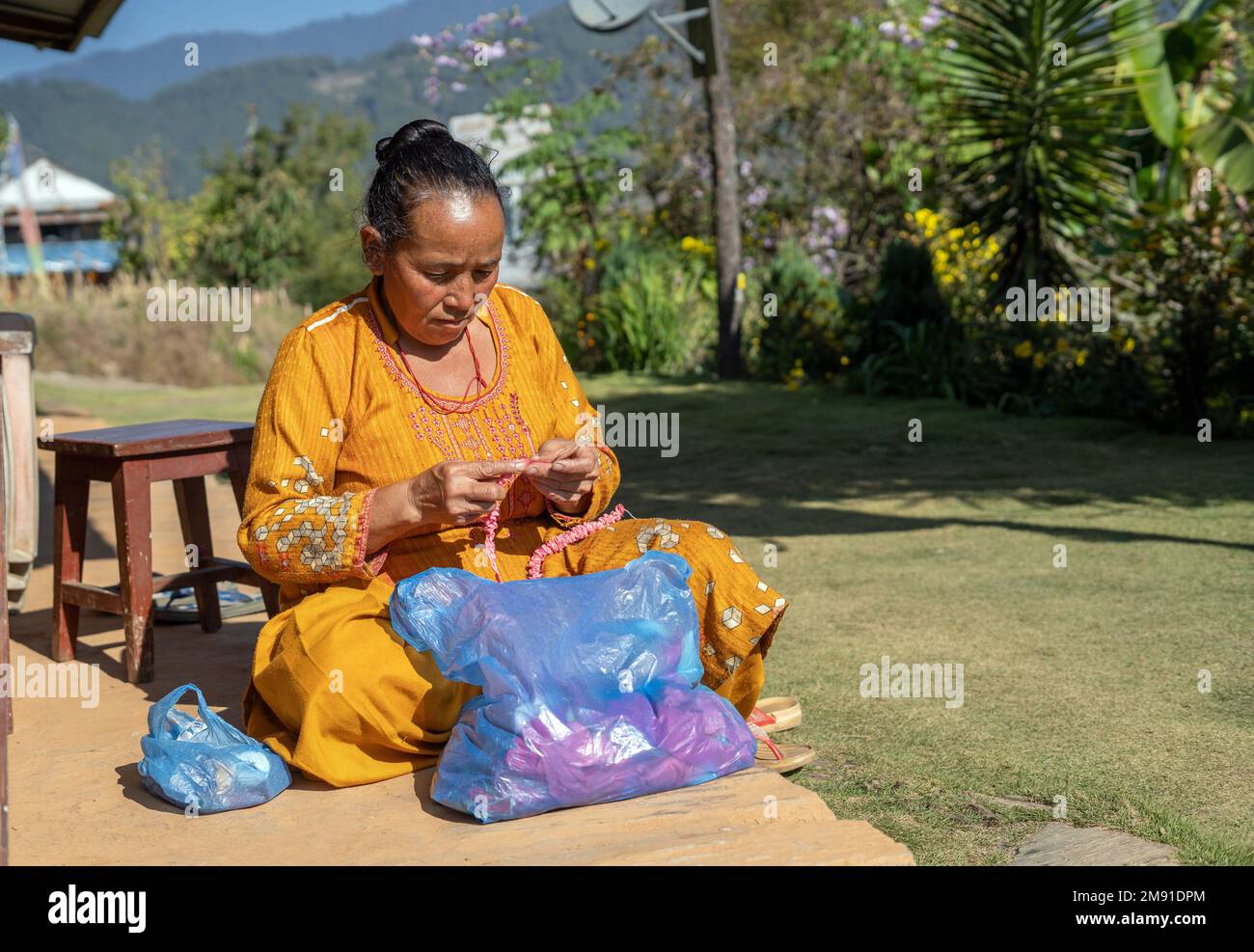 Dolakha District, Nepal - 2022. Dezember - Seniorin zu Hause im Hinterhof mit Wollknoten Stockfoto