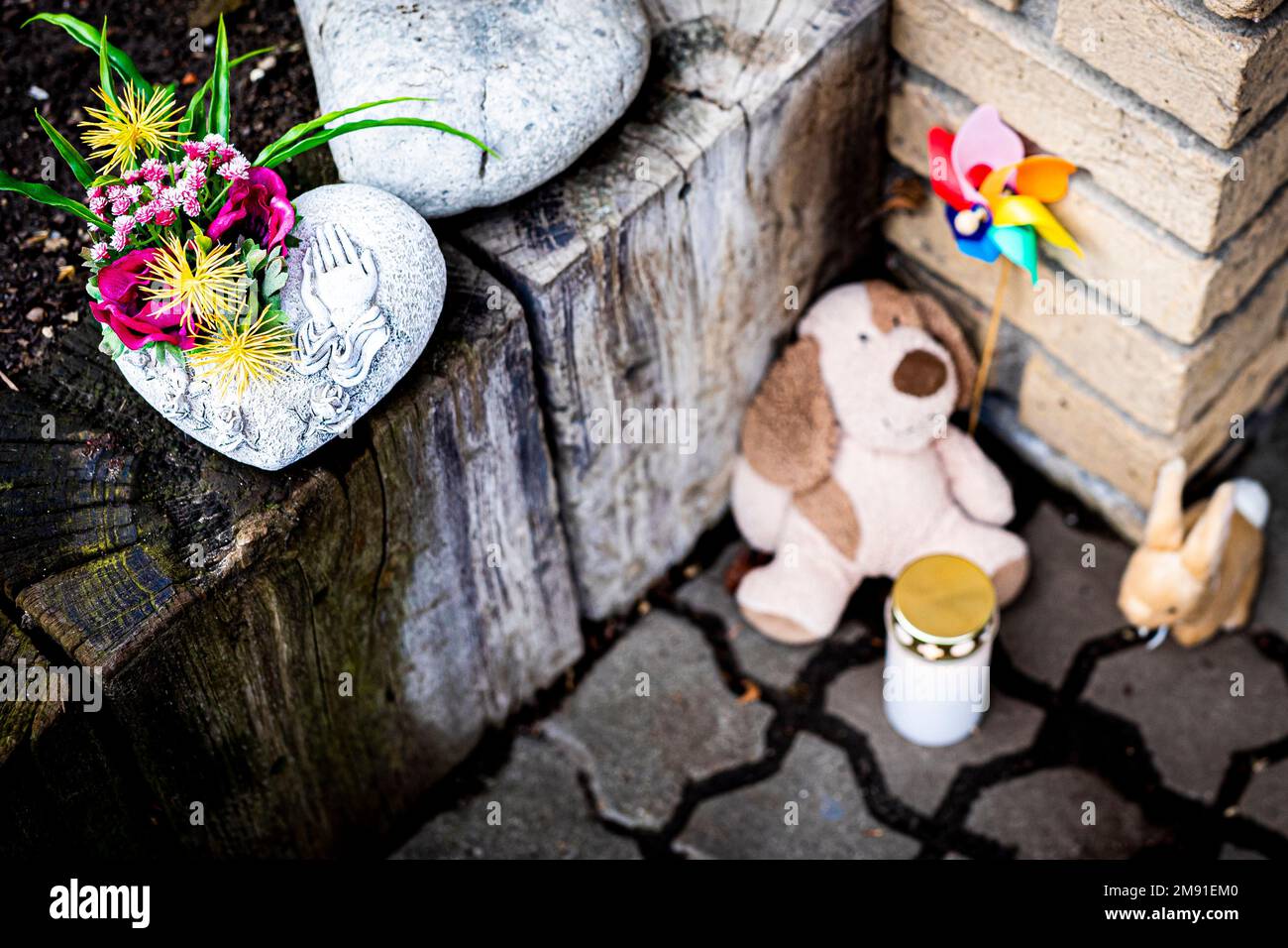 Barsinghausen, Deutschland. 16. Januar 2023. Blumen, zwei Plüschtiere und  ein Windspiel liegen neben einer Grabkerze an einem Hauseingang in der  Region Hannover. Nach dem Tod eines vierjährigen Jungen in Barsinghausen  richten sich