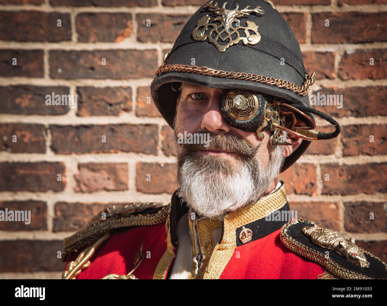 Porträt eines aussehenden Mannes mit grauem Bart. Er trägt eine Militäruniform und ein futuristisches Steampunk-Monokel. Stockfoto