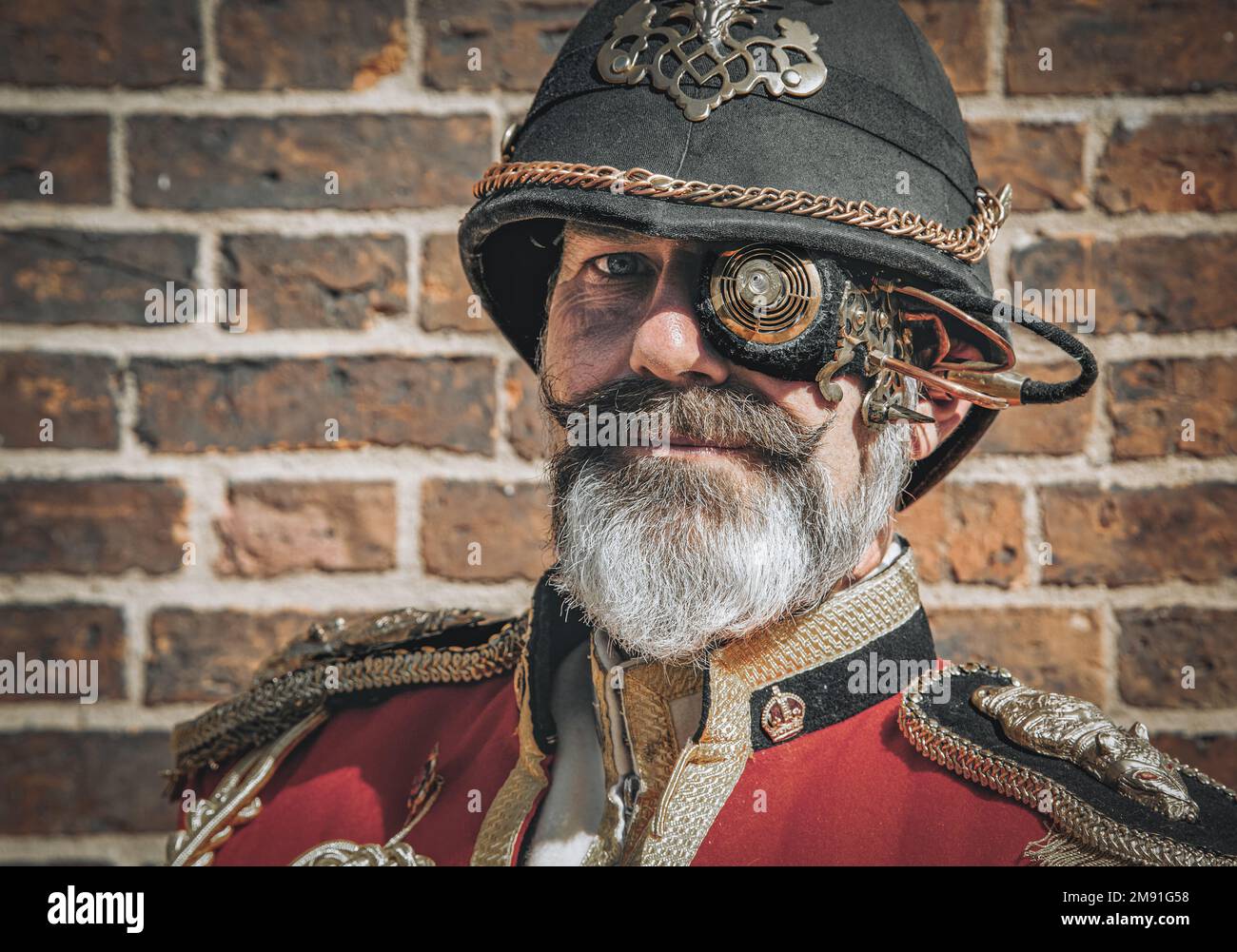 Porträt eines aussehenden Mannes mit grauem Bart. Er trägt eine Militäruniform und ein futuristisches Steampunk-Monokel. Stockfoto