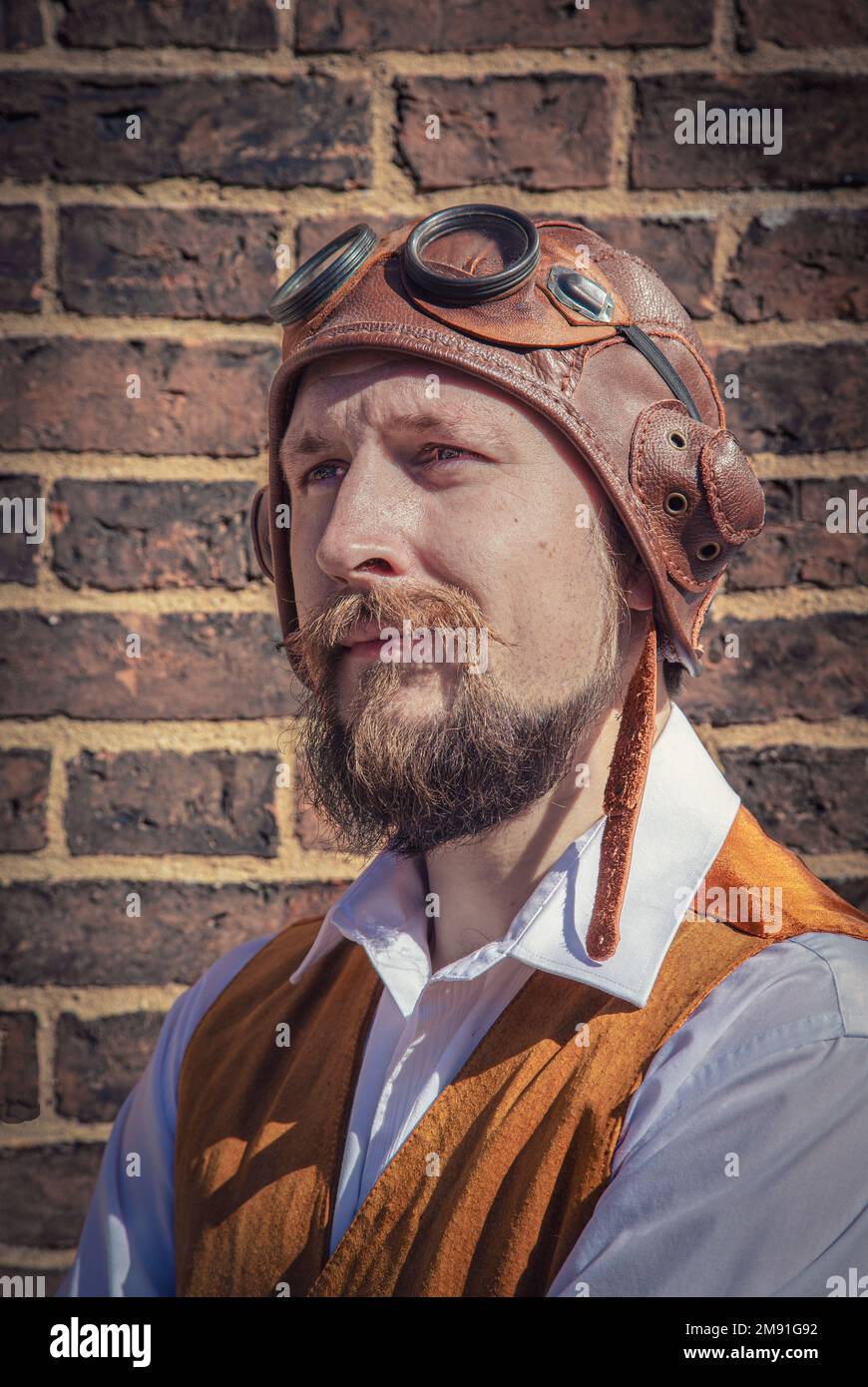 Porträt eines heldenhaft aussehenden Mannes mit Bart. Er trägt einen alten Flughelm. Steampunk-Pilot, Abenteurer, Entdecker. Stockfoto