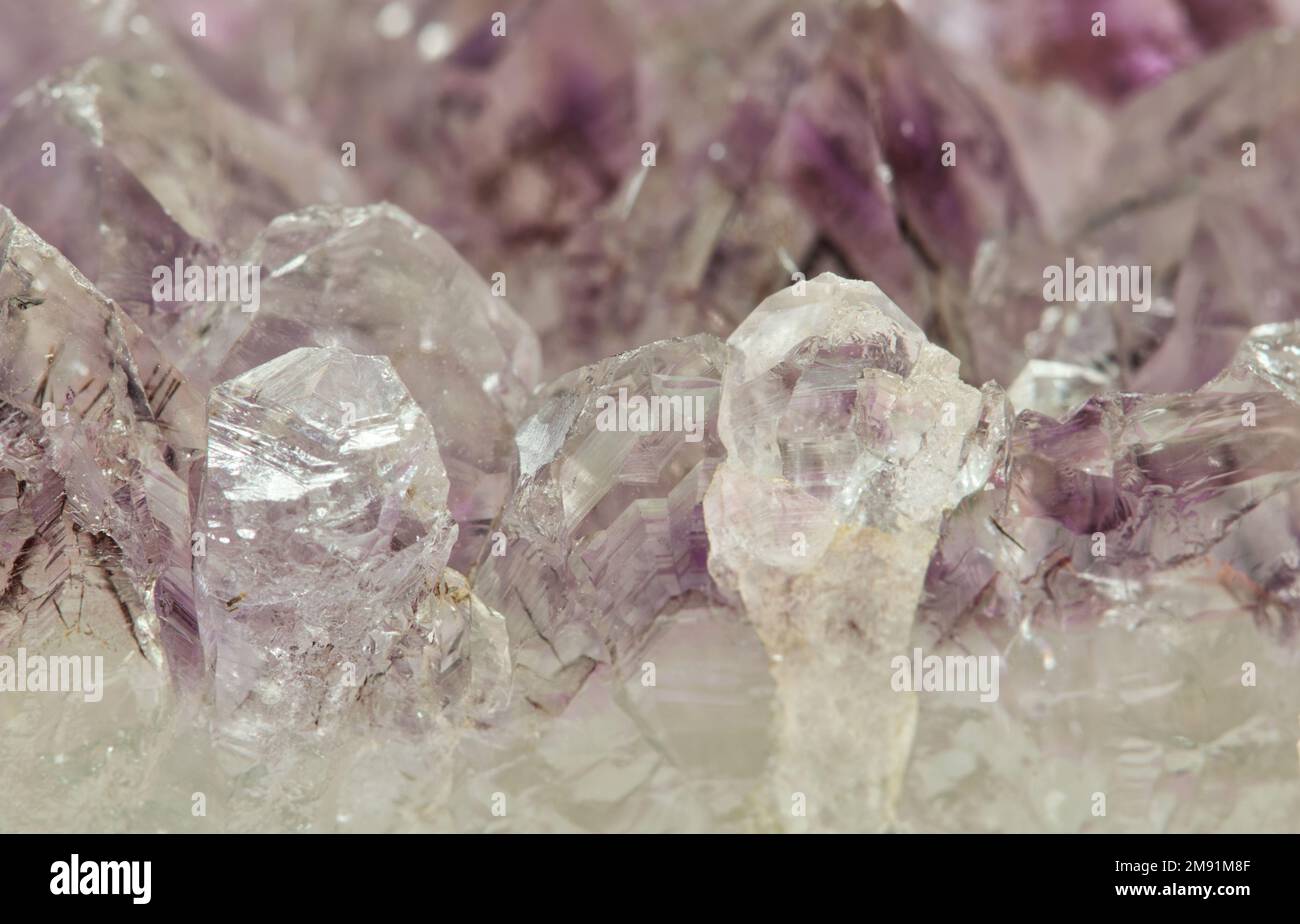 Helle, blassfarbene Amethyst-Quarz-Kristalle in Rohmineralform. Feine Details und Texturen bieten einen abstrakten Hintergrund. Stockfoto