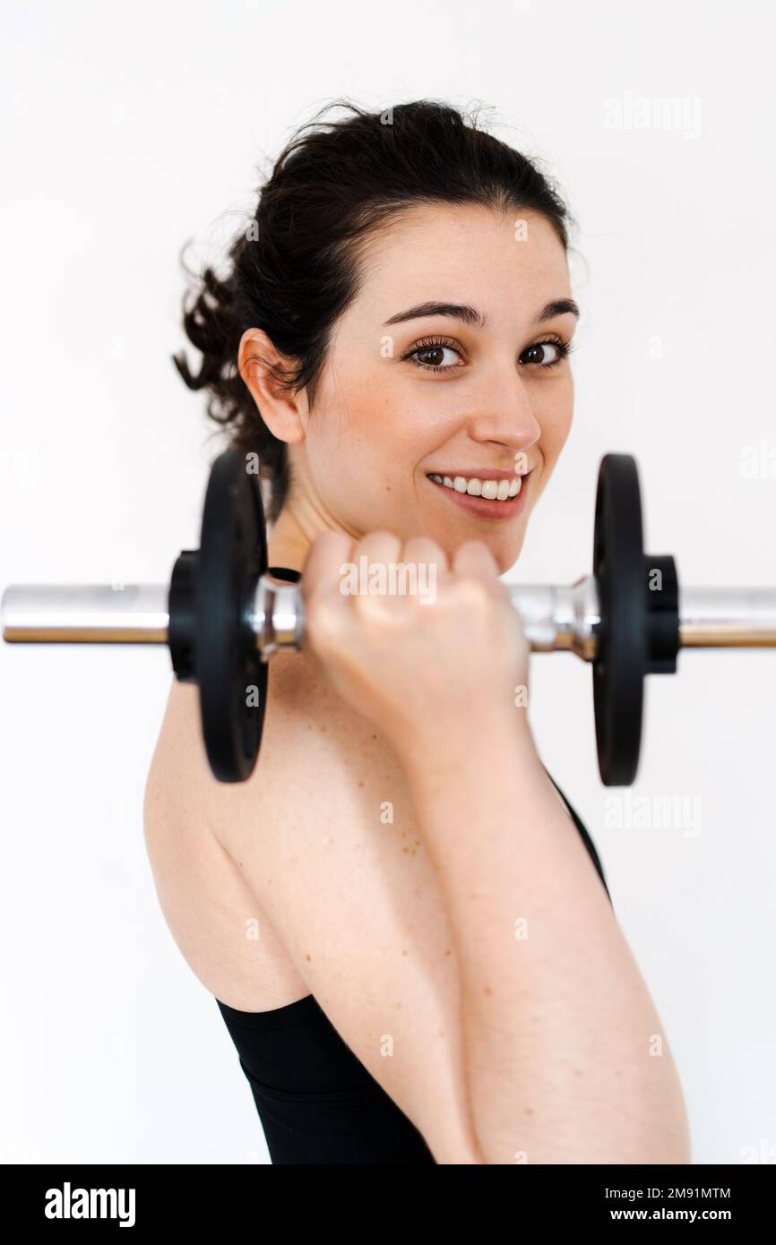 Junge, schöne, glückliche Frau, die zu Hause trainiert, mit einer Hantelglocke, die fit ist Stockfoto