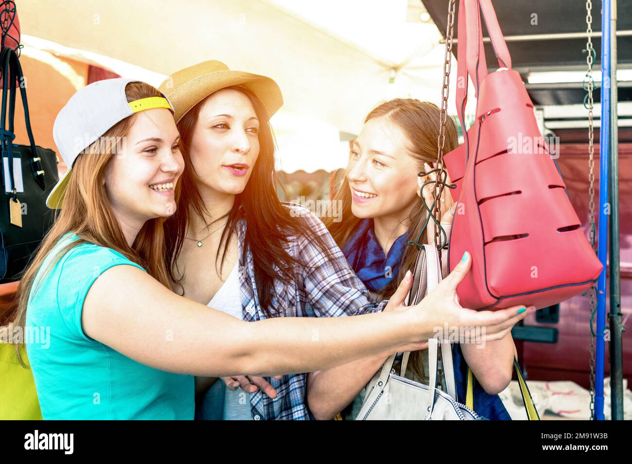 Junge, schöne Frauen, Freundinnen auf dem Flohmarkt, die nach Modetaschen suchen - beste Freundinnen, die Spaß haben und in der Altstadt einkaufen - lebhaftes Kreuz Stockfoto