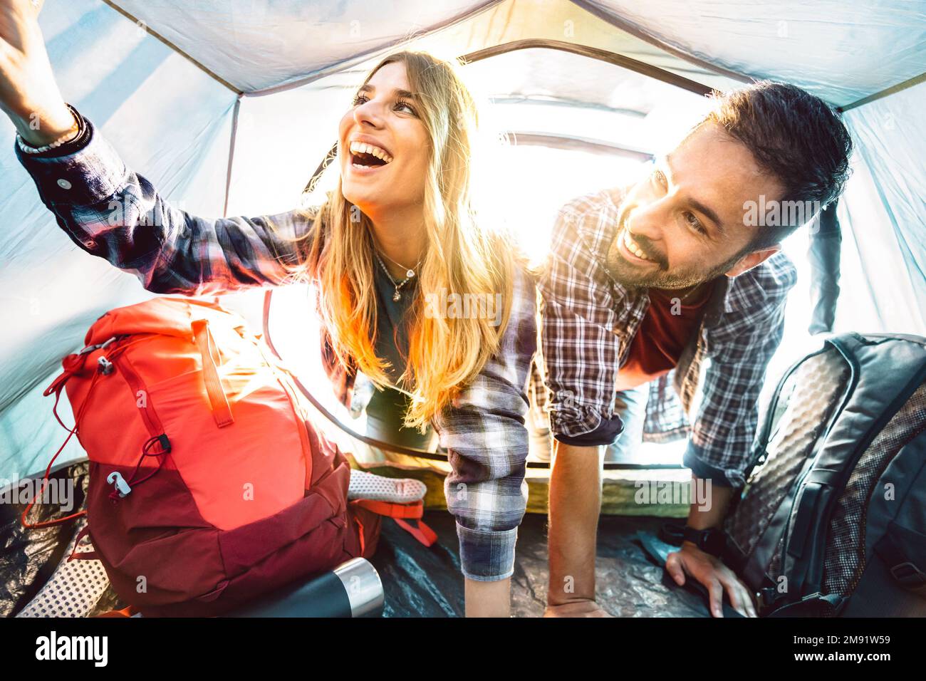 Ein Blick auf ein glückliches Paar im Campingzelt bei Sonnenuntergang - Abenteuer und Liebe Lebensstil Konzept auf Reisen - Junge Leute haben Spaß Stockfoto
