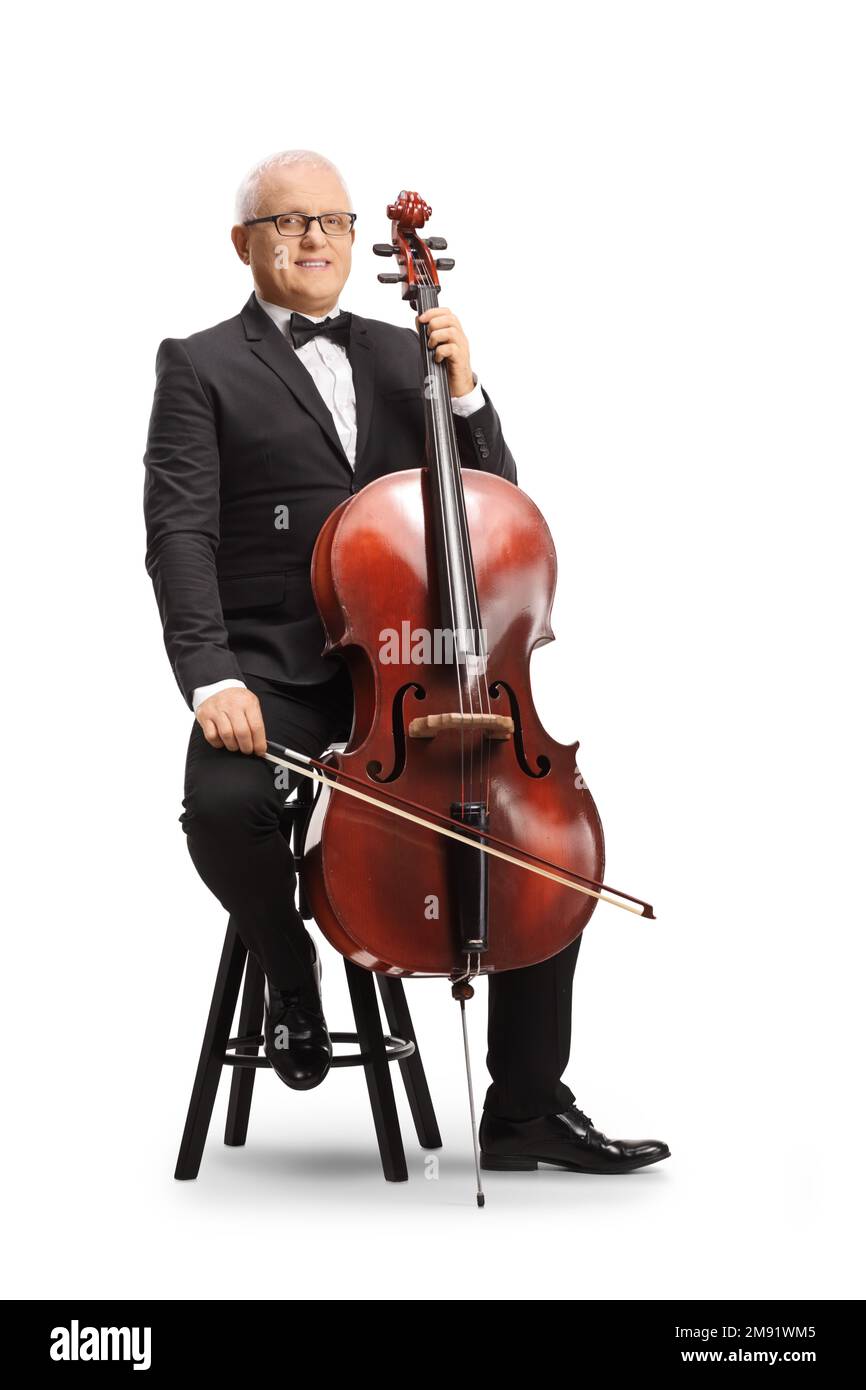 Langes Porträt eines Musikers in schwarzem Anzug und Fliege, der auf einem Stuhl mit Cello sitzt und isoliert auf weißem Hintergrund lächelt Stockfoto