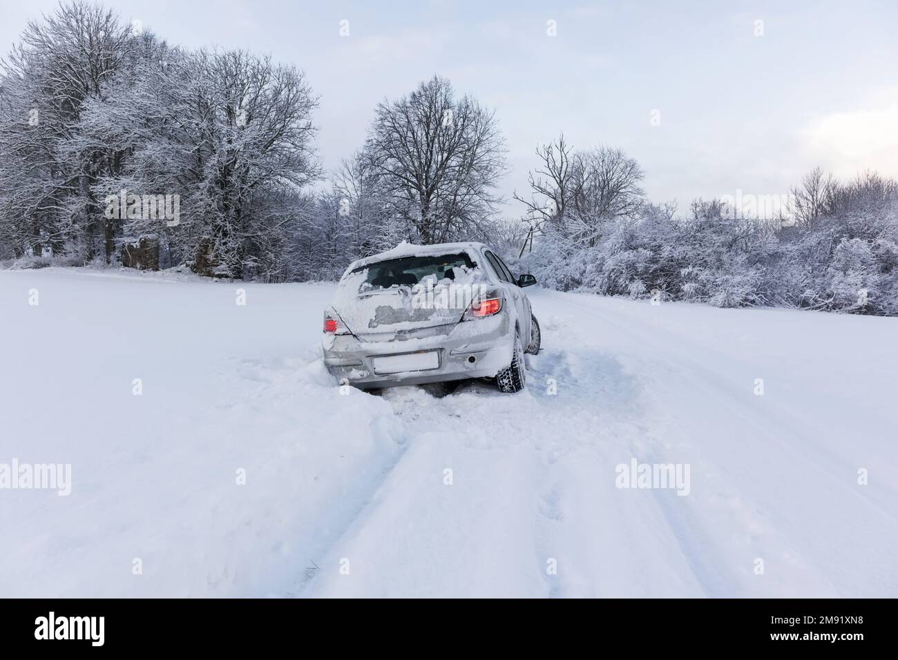 Ein graues Auto ist an einem Wintertag auf einer rutschigen und verschneiten Straße gestürzt. Stockfoto