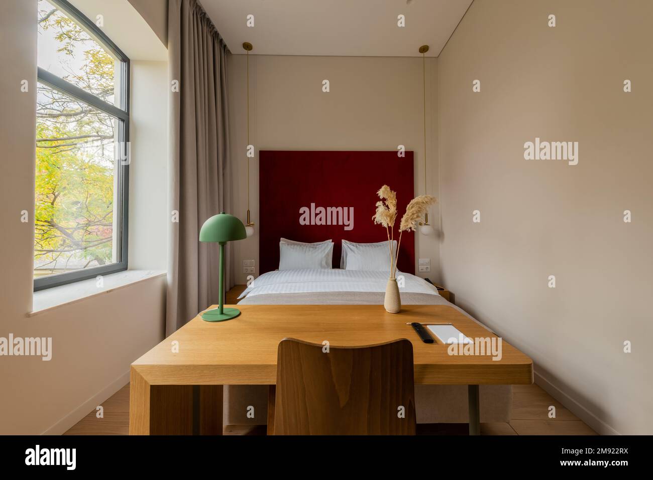 Holzschreibtisch und Stuhl in der Nähe eines komfortablen Bettes im Hotelzimmer, Bild der Stock Stockfoto