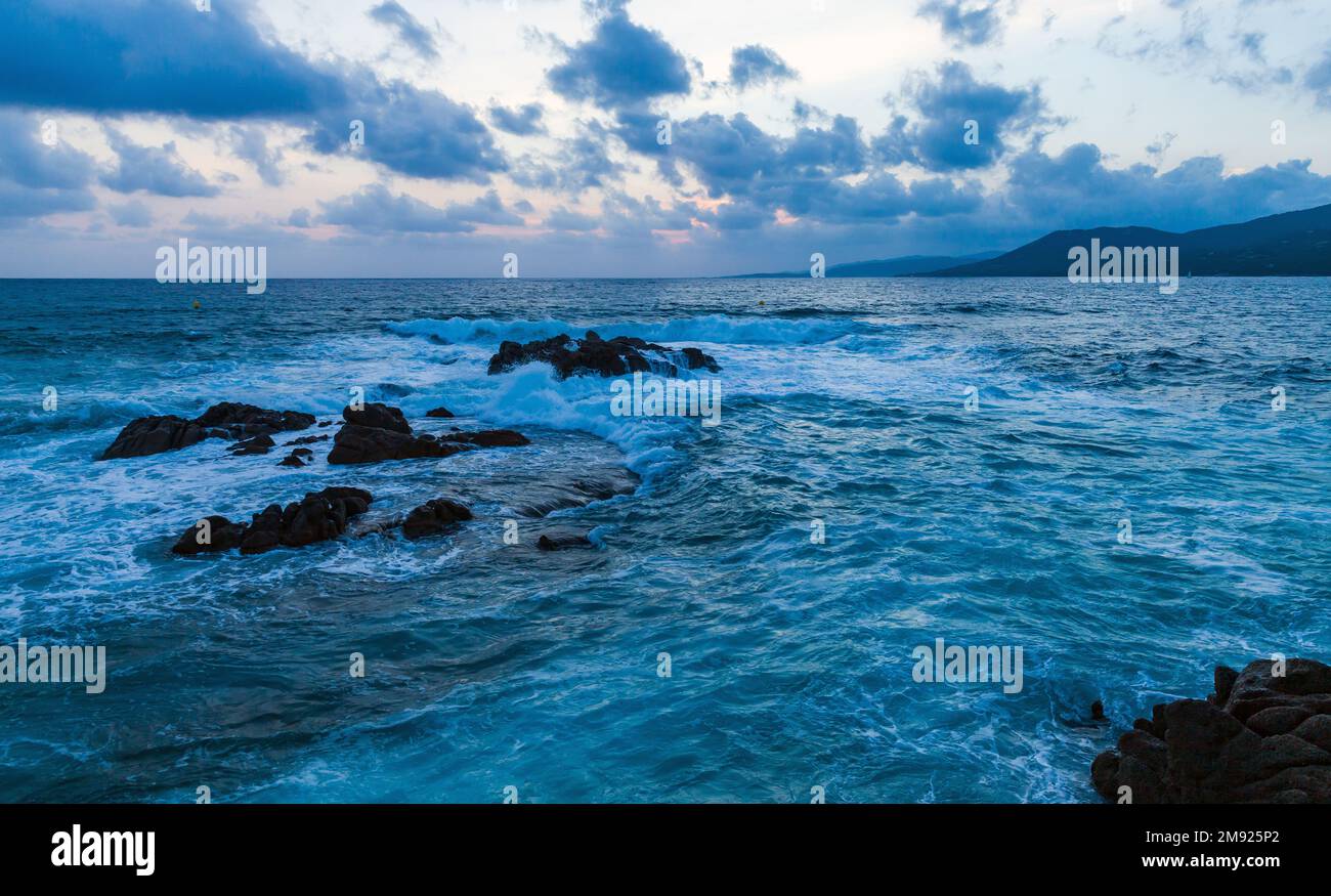 Dramatische Küstenlandschaft mit Wellen und Felsen am Abend. Propriano, Korsika, Frankreich Stockfoto