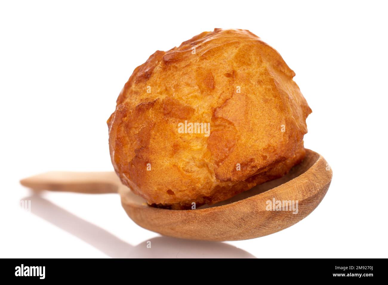 Mehrere süße Chouquettes mit einem Holzlöffel auf weißem Hintergrund. Stockfoto