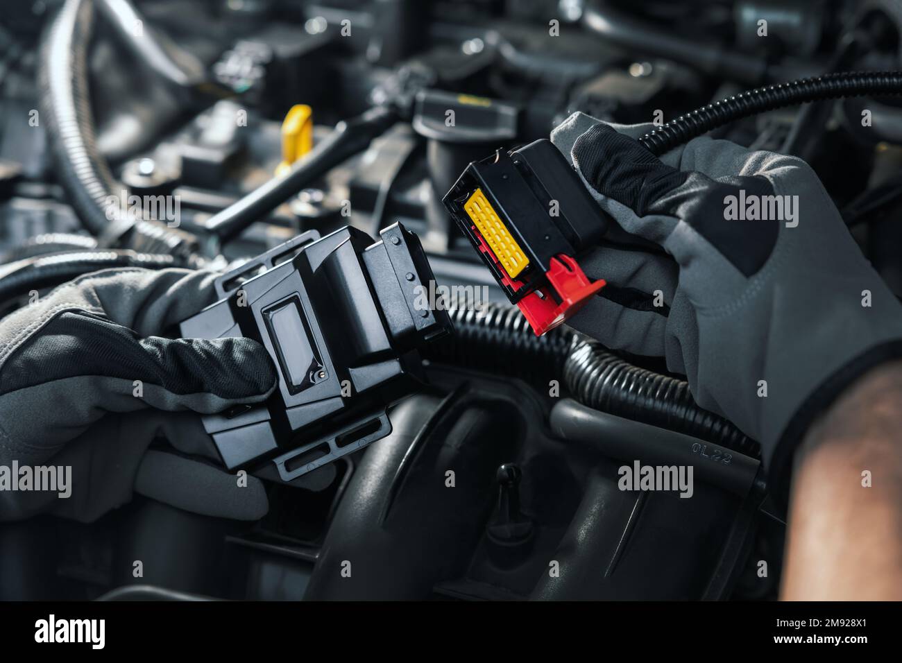 Mechaniker, der eine Chip-Tuning-Box am Automotor installiert Stockfoto