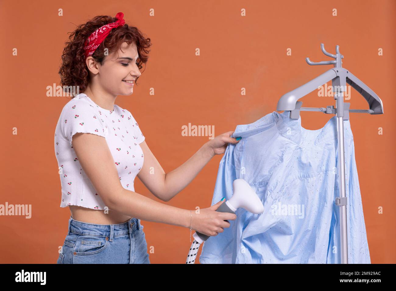 Ein Lächeln auf deinem Gesicht. Ein Dampfgarer zum Bügeln. Ein Mädchen mit Locken. Stockfoto