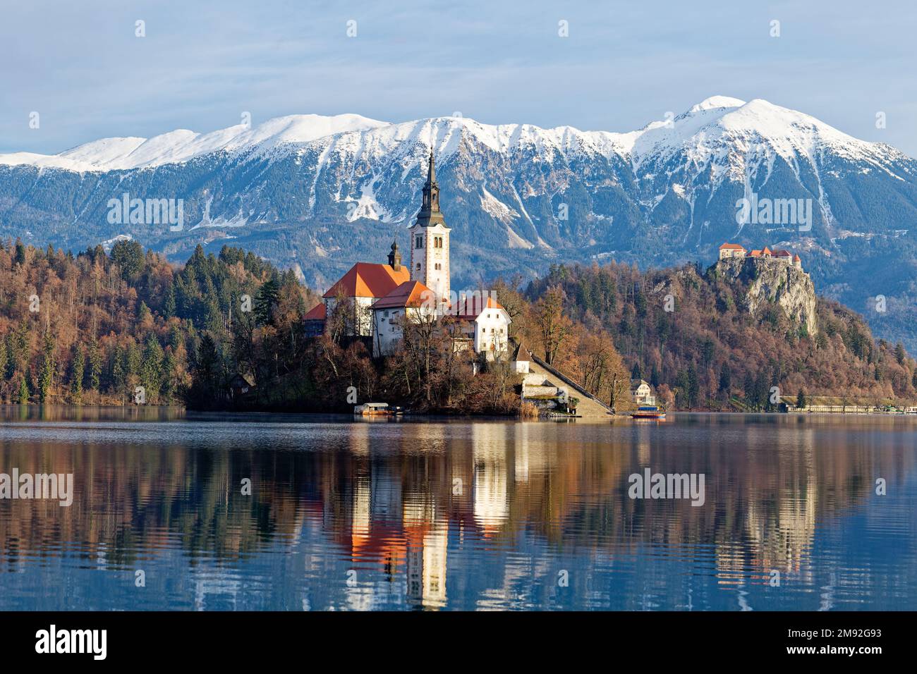 Winterlandschaft bei Sonnenaufgang am magischen Bleder See in Slowenien. Eine Wintergeschichte für romantische Erlebnisse. Berge mit Schnee im Hintergrund. Stockfoto