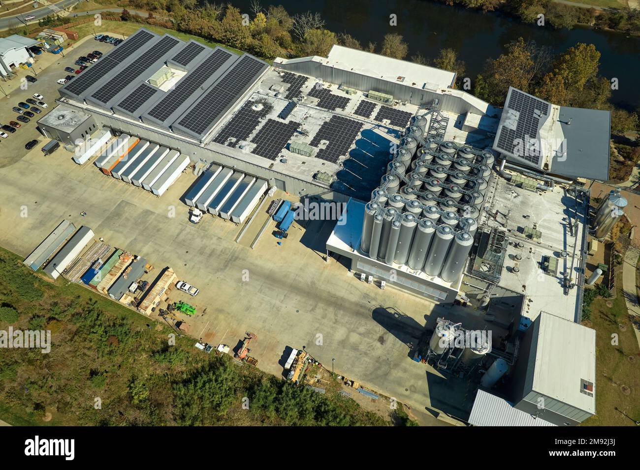 Luftaufnahme eines Solarkraftwerks mit blauen Photovoltaik-Paneelen, die auf dem Dach eines Industriegebäudes montiert sind, um ökologischen Ökostrom zu erzeugen Stockfoto