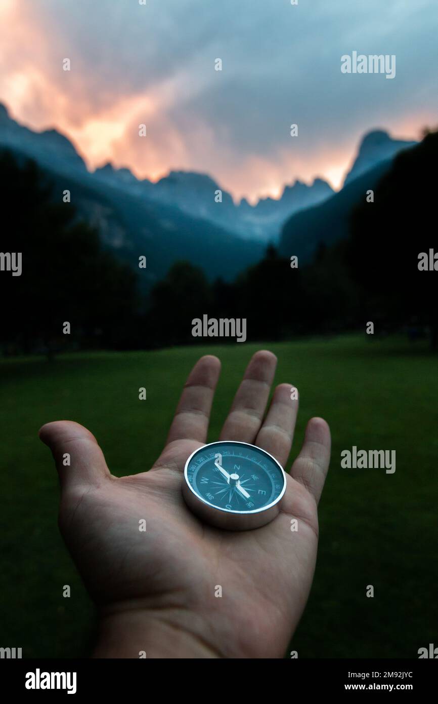 Der Kompass wird mit einer Hand in einer Berglandschaft gehalten. Konzept von Reisen, Freiheit, Lebensstil. Stockfoto